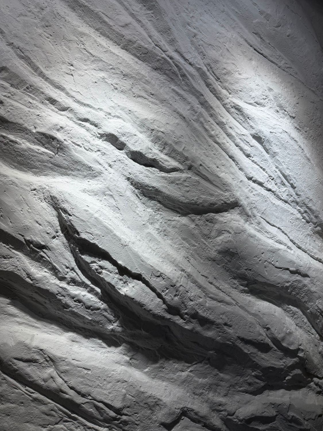 Close-up of a sculpted Stone Craft feature wall under a spotlight