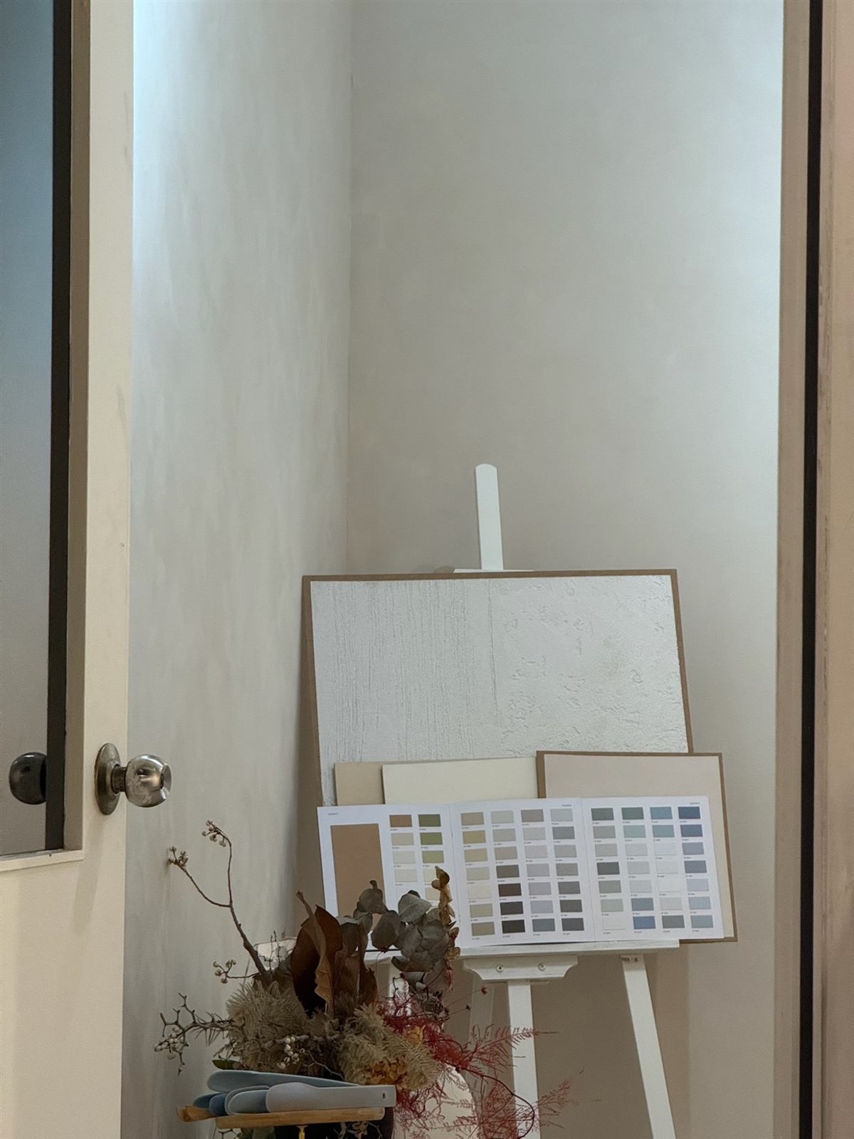 A quiet corner of the showroom: lime-finished walls, a sample board and colour charts on an easel